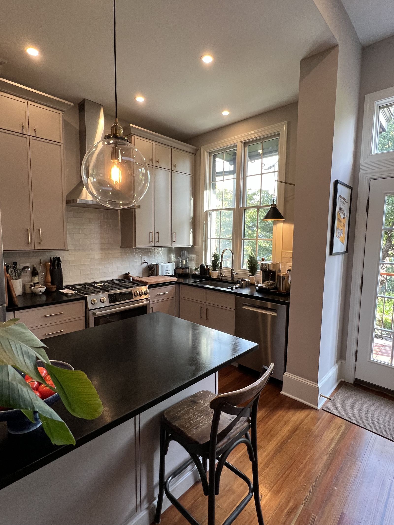 Warm gray kitchen with glass globe pendant, black countertops and natural light, Bolton Hill MD