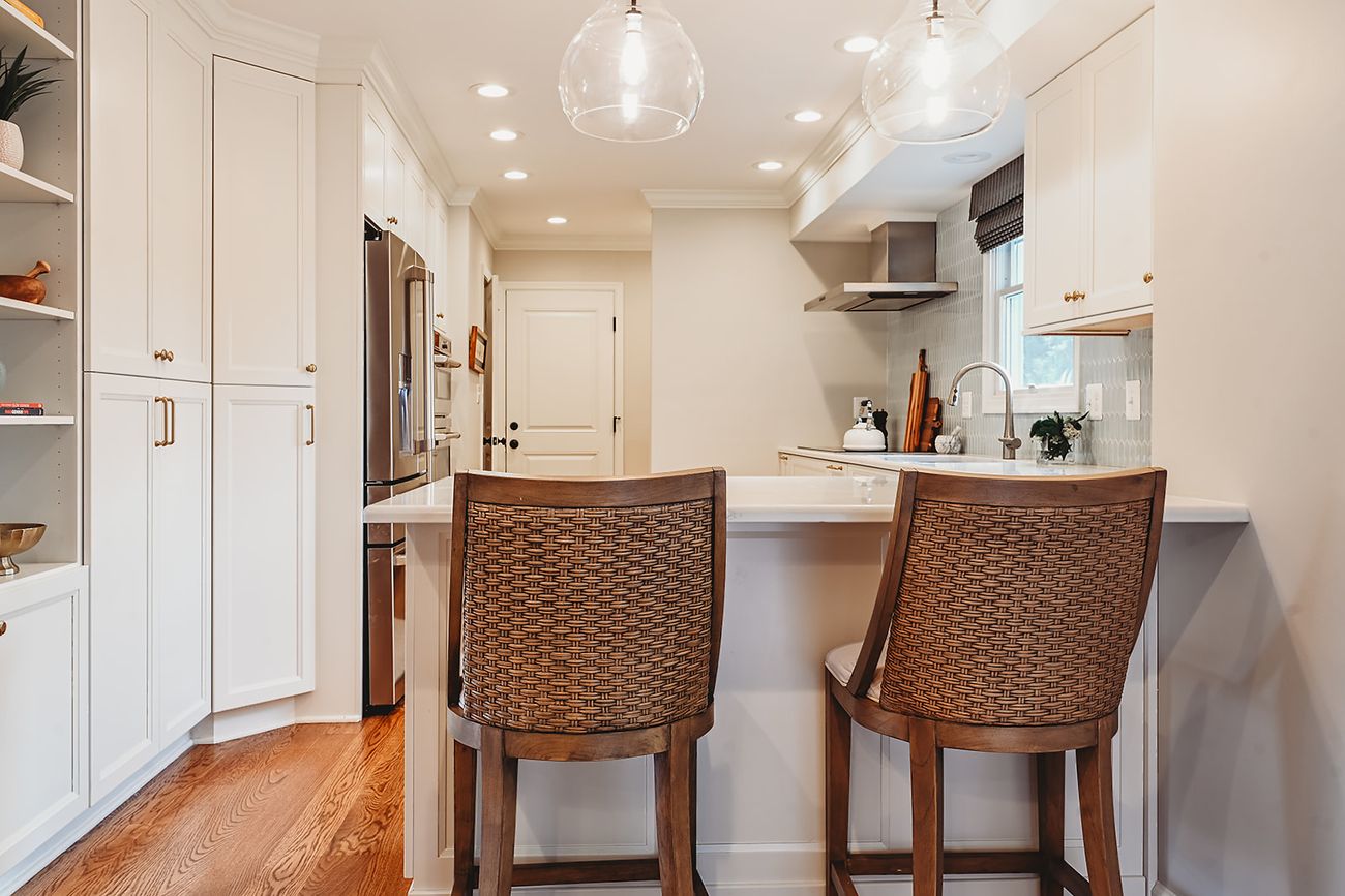 Bright white kitchen with glass pendants and woven counter stools, Ellicott City MD